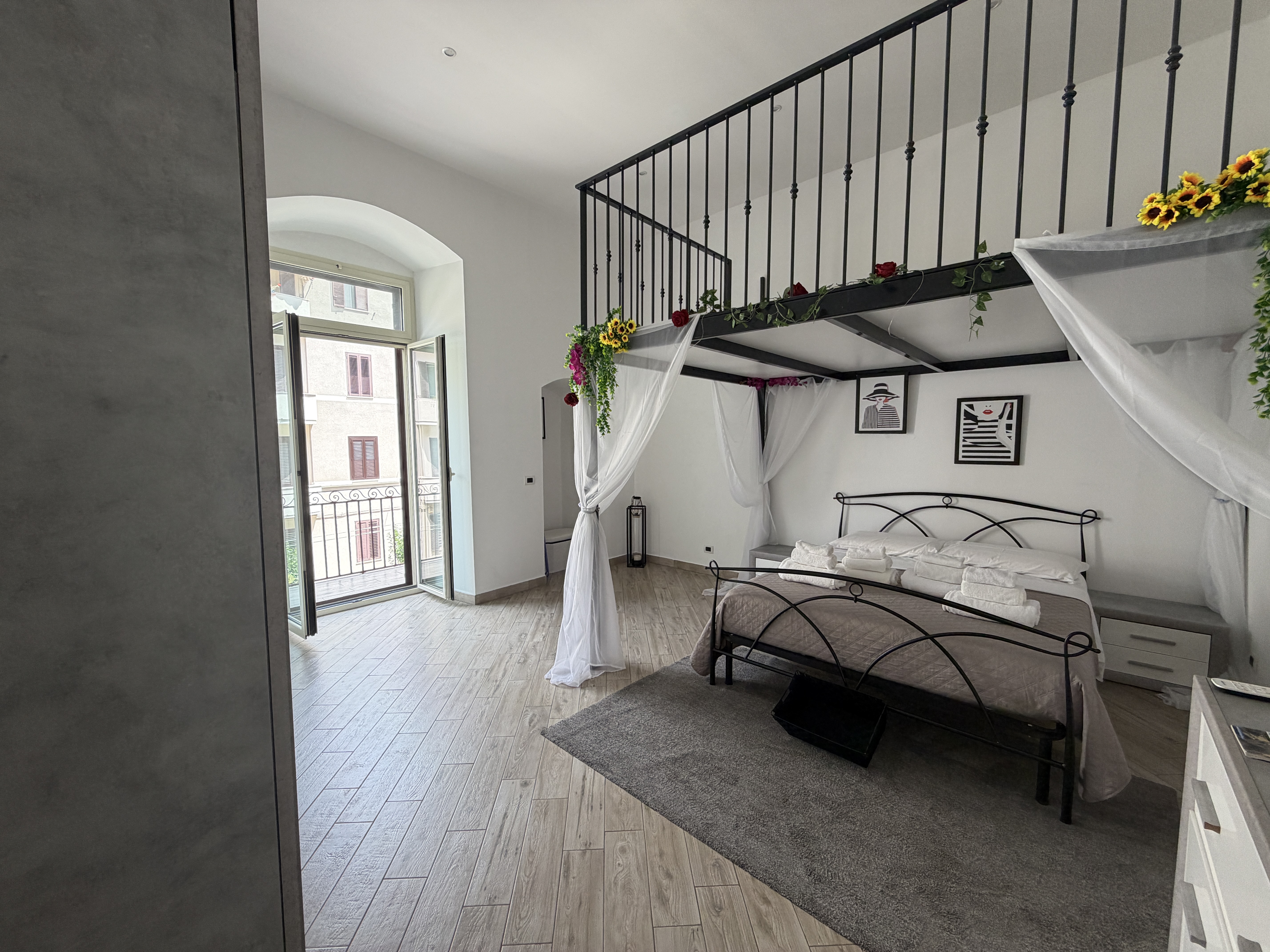Camera luminosa della Maison di Eva con letto in ferro battuto e luce dal balcone