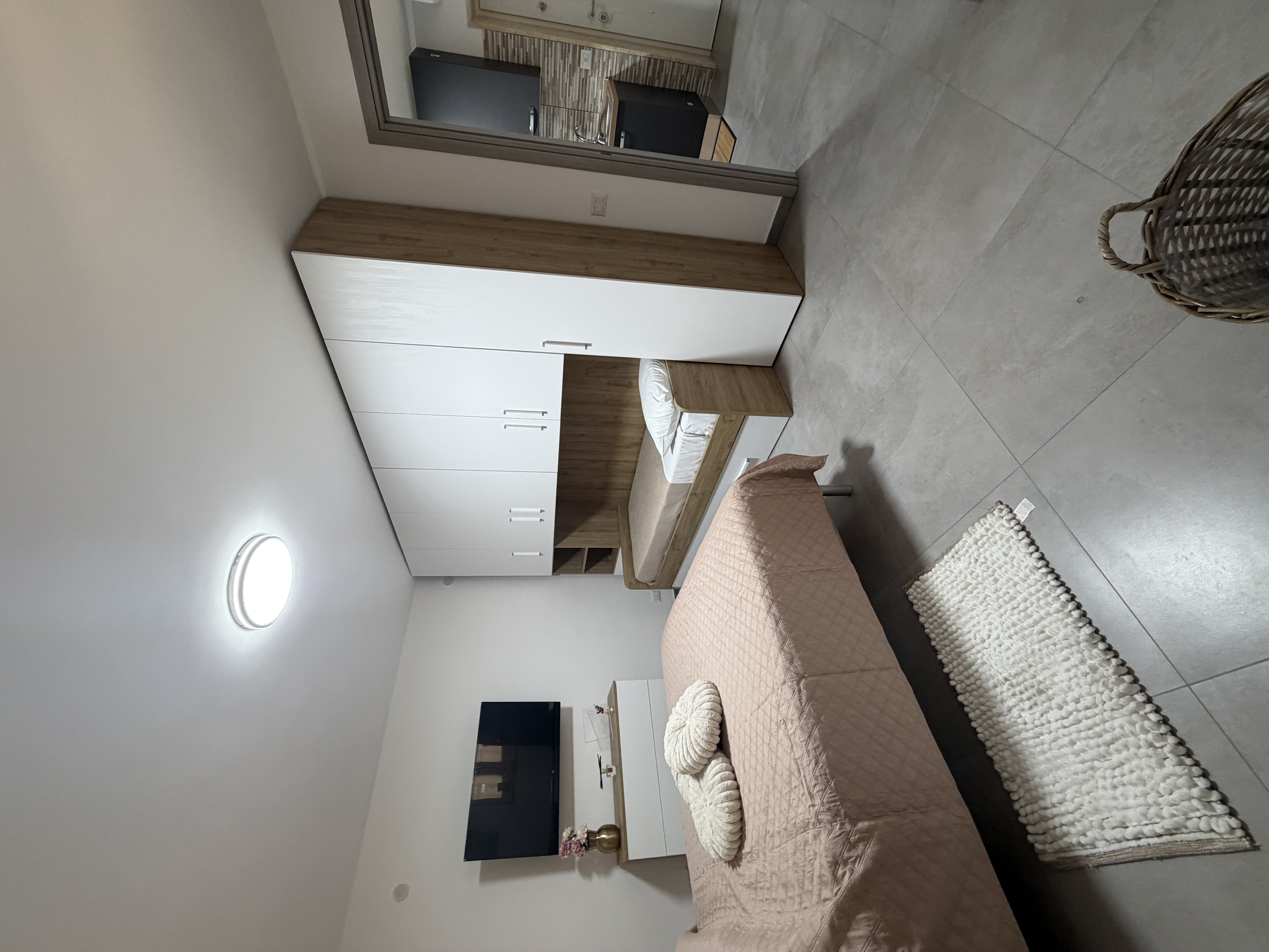 Camera da letto con specchio e mobili in legno chiaro